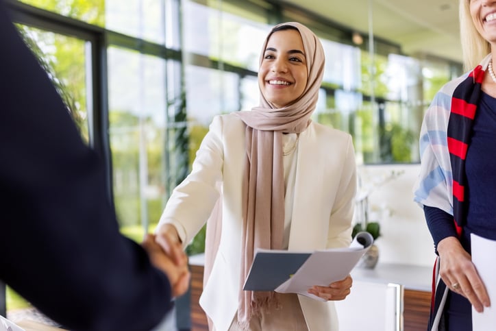 Smiling Muslim businesswoman shaking hands with partner